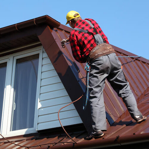 Roofer works on metal roof.