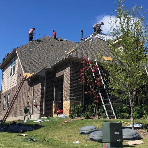 A roofer works on a shingle roof.