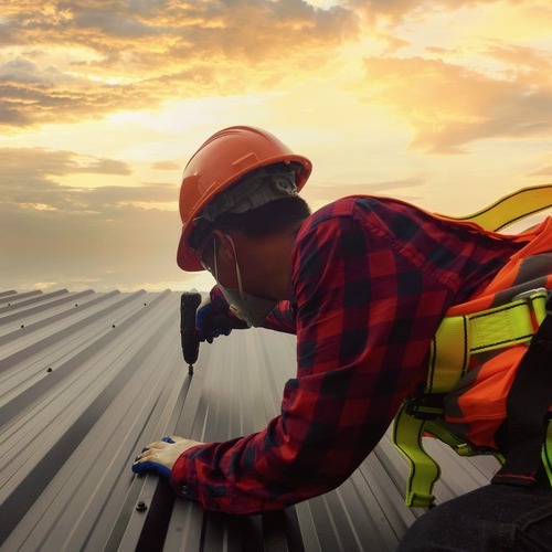 Roofer installs metal roofing.